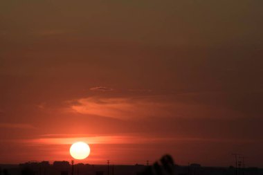 Gün batımında, büyük bir şehrin üzerinde, gece ve uzun ve sıcak bir günün güçlü bir tezahüratıyla bitmemiş bir resmi.