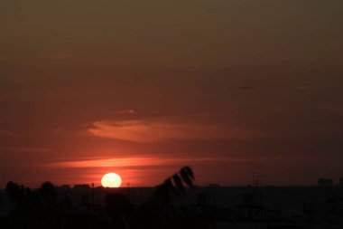 Gün batımında, büyük bir şehrin üzerinde, gece ve uzun ve sıcak bir günün güçlü bir tezahüratıyla bitmemiş bir resmi.