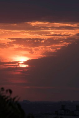 Gün batımında, büyük bir şehrin üzerinde, gece ve uzun ve sıcak bir günün güçlü bir tezahüratıyla bitmemiş bir resmi.