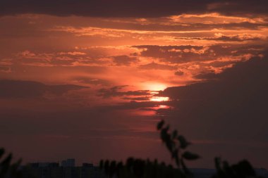 Gün batımında, büyük bir şehrin üzerinde, gece ve uzun ve sıcak bir günün güçlü bir tezahüratıyla bitmemiş bir resmi.