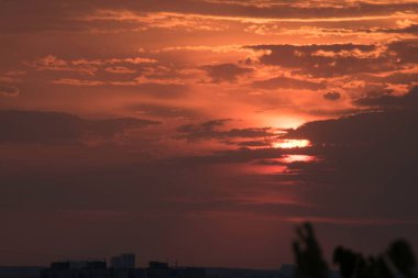 Gün batımında, büyük bir şehrin üzerinde, gece ve uzun ve sıcak bir günün güçlü bir tezahüratıyla bitmemiş bir resmi.