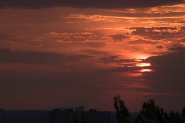 Gün batımında, büyük bir şehrin üzerinde, gece ve uzun ve sıcak bir günün güçlü bir tezahüratıyla bitmemiş bir resmi.