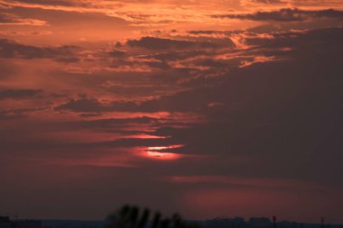 Gün batımında, büyük bir şehrin üzerinde, gece ve uzun ve sıcak bir günün güçlü bir tezahüratıyla bitmemiş bir resmi.