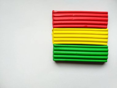 Farklı renklerin yakın plan plastikçini kopyalama alanı olan beyaz bir arkaplanda yatar. Çocuklar için Bolivya bayrağı gibi kırmızı, sarı, yeşil plastik. Çocukların yaratıcılığı. Okul hazırlığı.