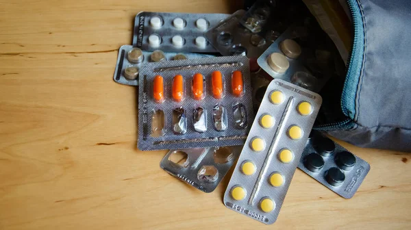 Close-up blisters with pills fall out of the medicine chest. Many blisters with different pills on a wooden background with copy space.