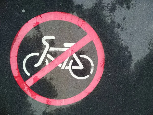 Sign on the asphalt prohibiting the movement of bicycles. No cycling in the pedestrian zone. Walkway only for pedestrians. Sign of crossed red circle and bike on the road after rain.