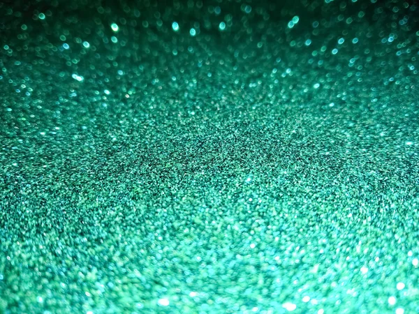 Green Glitter Selective Focus. Christmas abstract background. Defocused lights texture. Abstract bokeh lights. Shiny sparkle emerald metallic glitter texture. Glamorous luxurious color abstract background for you design project.