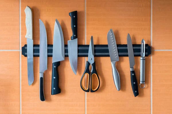 Cuchillos cuelgan de un soporte de imán. pared de cocina naranja — Foto de Stock