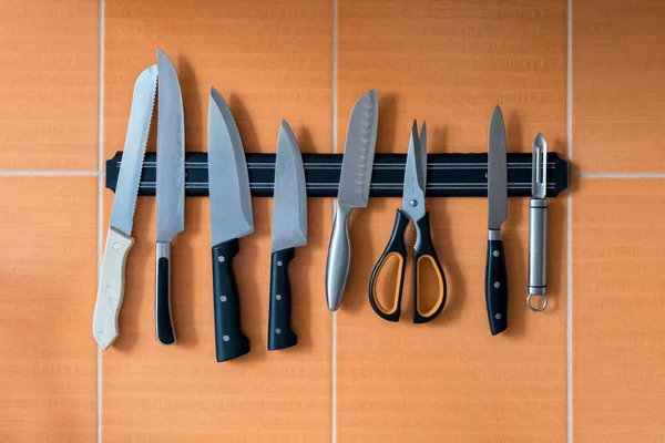 Cuchillos cuelgan de un soporte de imán. pared de cocina naranja — Foto de Stock