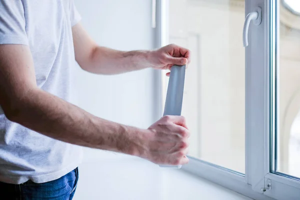 Рабочий наклеивает изоленту на окно в доме — стоковое фото