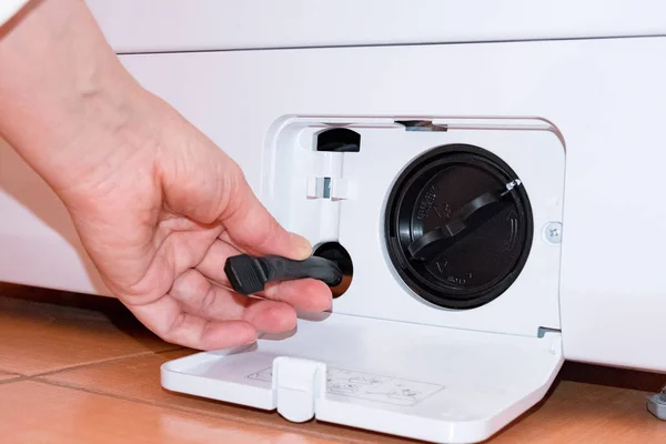 Lavadora con una tapa de filtro abierta, sostiene la mano parte, llave, parte — Foto de Stock