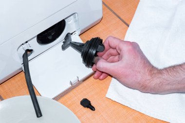 Çamaşır makinesi filtresinin açık kapağı. Çamaşır makinesinin tamir çalışmaları