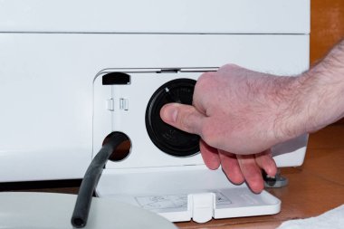 Çamaşır makinesi filtresinin açık kapağı. Çamaşır makinesinin tamir çalışmaları