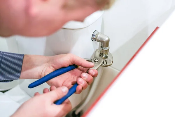 Sanitary worker performs repair of toilet bowl Stock Image