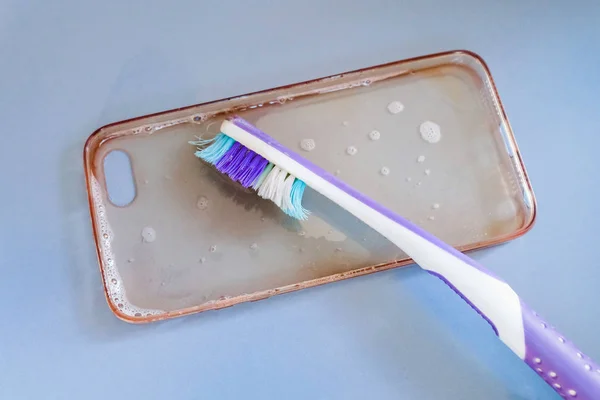 Чистка силиконового телефона с помощью зубной щетки, пены и мыла — стоковое фото