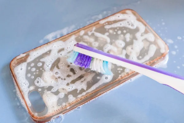 Reinigung der Silikontasche mit Zahnbürste, Schaum und Seife — Stockfoto