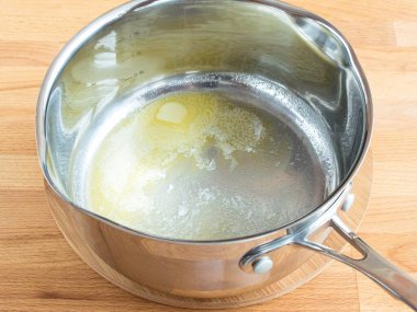 Tereyağı bir kepçenin içinde erir. Tavanın altında sarı tereyağı var. Yemek pişirme.