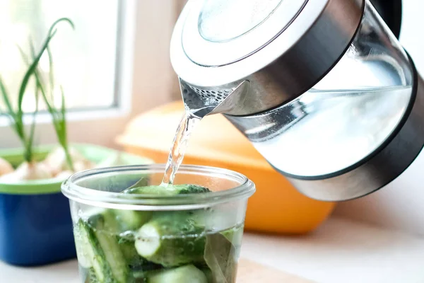 Pour water from a kettle into a jar of cucumbers. Preparation for the winter. — Stock Image Pour Water Kettle Jar Cucumbers Preparation Winter Stock Picture