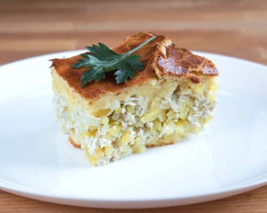 Beyaz tabakta patatesli bir parça etli turta.