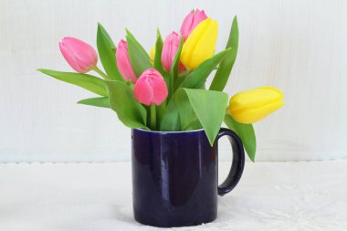 Lacivert mug içinde pembe ve sarı laleler