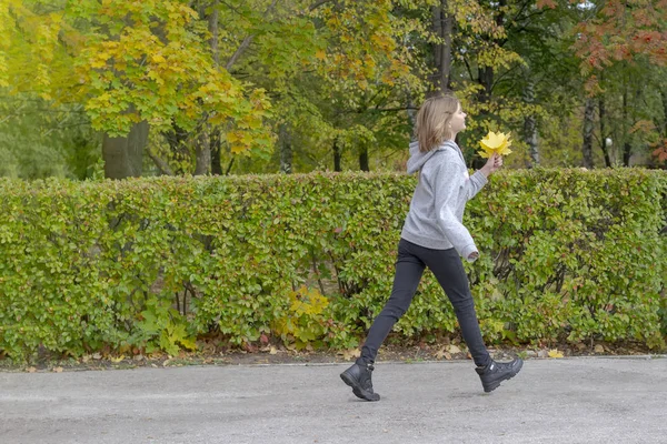 若い美しい女性が公園で紅葉と遊んでいます — ストック写真