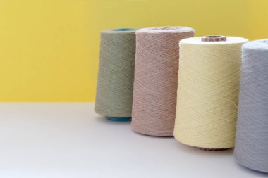 Sarı bir arka plan üzerinde el ve makine örme için yün iplik pastel renk bobinler