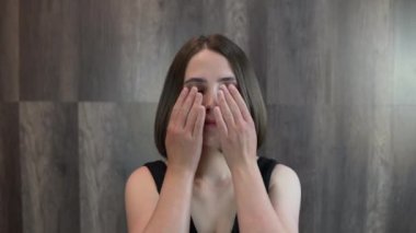 Kız elleriyle gözlerini ovuyor ve yüzüne makyaj yapıyor.