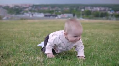 Çocuk dışarıda, çimlerde sürünüyor.