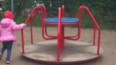 Kız atlıkarıncanın etrafında koşuyor ve dönüyor. Rus oyun alanı