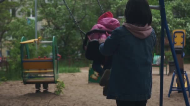 Mãe Jovem Empurra Filha Balanço Menina Parque Infantil — Vídeo de Stock