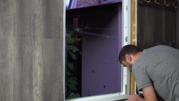 A man seals the window with construction foam. Installing the window yourself — Stock Footage Man Seals Window Construction Foam Installing Window Yourself Video Clip