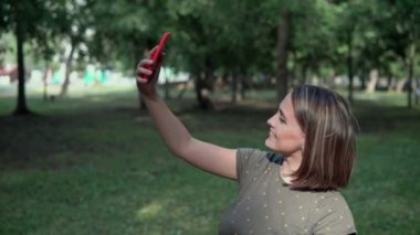 Genç bir kız doğada selfie çeker. Kız telefonda kanalın fotoğraflarını çekiyor. 4K