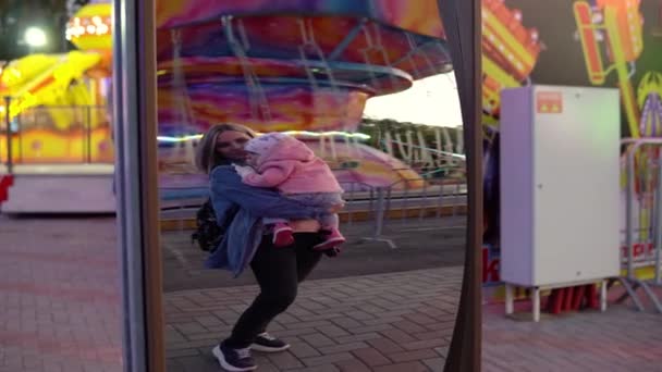 Een vrouw met een kind in haar armen in het park staat voor een scheve spiegel — Stockvideo
