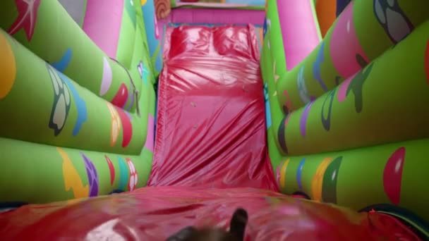 Dziewczyna jeździ na nadmuchiwanym zjeżdżalni na placu zabaw — Wideo stockowe