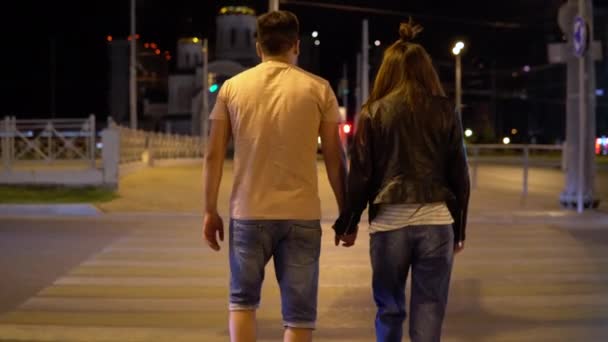 Para trzymająca się za rękę spacerująca wieczorem po drodze dla pieszych — Wideo stockowe