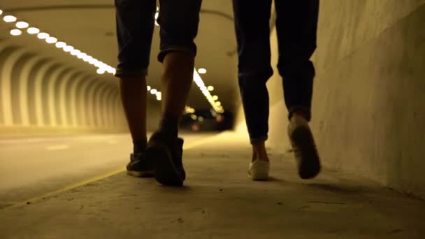 Een paar wandelingen in de late avond door een verlichte tunnel — Stockvideo