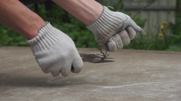 Een man buigt de draad met een tang. Handen dicht.. — Stockvideo