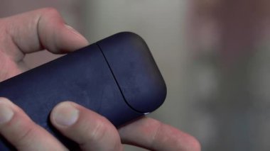 Bir el elektronik sigaranın şarj kutusunu açar. Yakın plan.