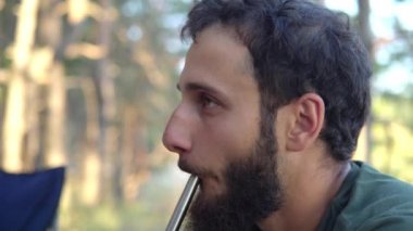 Sakallı genç adam nargile içiyor.