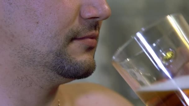 Nieporządnie. nieogolony mężczyzna pije piwo z przezroczystego kubka w domu — Wideo stockowe