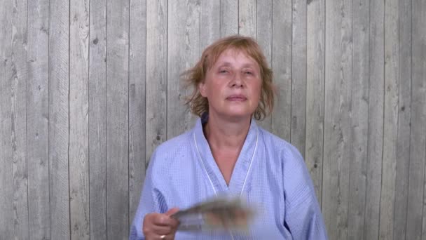 Kvinnan i rummet undviker hettan. Skapar en konstgjord vind med fläkt. — Stockvideo