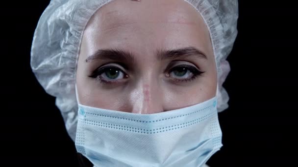 Tired nurse looking at camera on black background — Stock Video