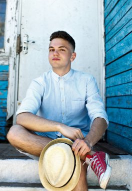 Genç bir adam adımlar ve gülümsüyor üzerinde oturur, o eski köy.