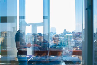 Üç adam camdan görülmektedir. Büyük şehrin penceresinde görünür yansımasıdır.