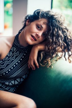 Yaz günü. Güzel kıvırcık kadın tatil köyünün terasındaki kanepede dinleniyor. 