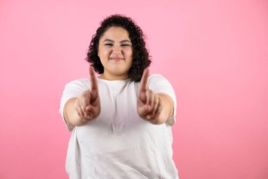 Pembe soyutlanmış arka planda genç bir kadın parmaklarıyla hayır diyor, kızgın ve hayal kırıklığı dolu bir ifade.