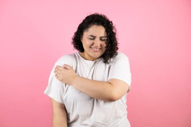 Omzunda çiş olan ve pembe arka planda acı dolu bir ifade olan genç ve güzel bir kadın..