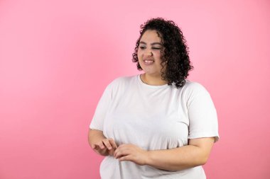 Dışlanmış pembe arka planda duran genç ve güzel bir kadın. İğrenç bir ifadeyle.