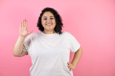 Genç ve güzel bir kadın pembe arka planda sırıtarak şarkı söylemeyi kesiyor..