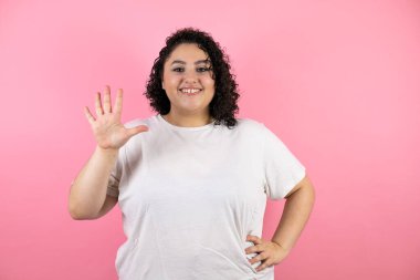Güzel genç bir kadın beş numarayı gösterip işaret ederken kendinden emin ve mutlu bir şekilde gülümsüyor.